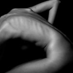 a naked woman sitting on a table with her back to the camera